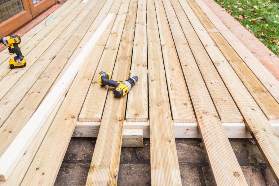 Wooden deck boards under construction with cordless drills on a backyard deck frame