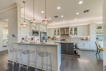 Spacious modern kitchen with white cabinets, island seating, pendant lights, and hardwood floors